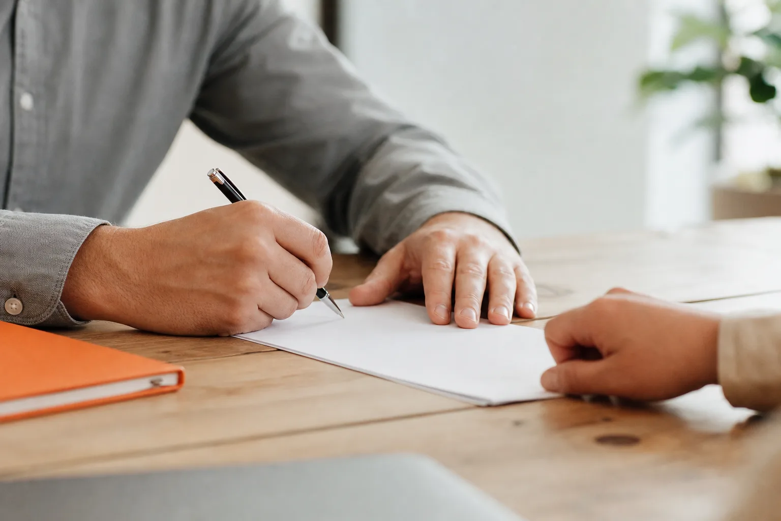 Manos firmando un contrato sobre la mesa
